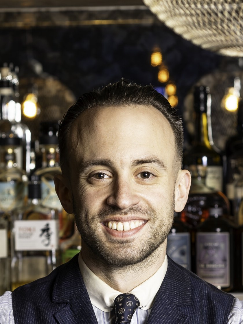 Ben Yabrow behind a well-stocked bar, ready to craft drinks.