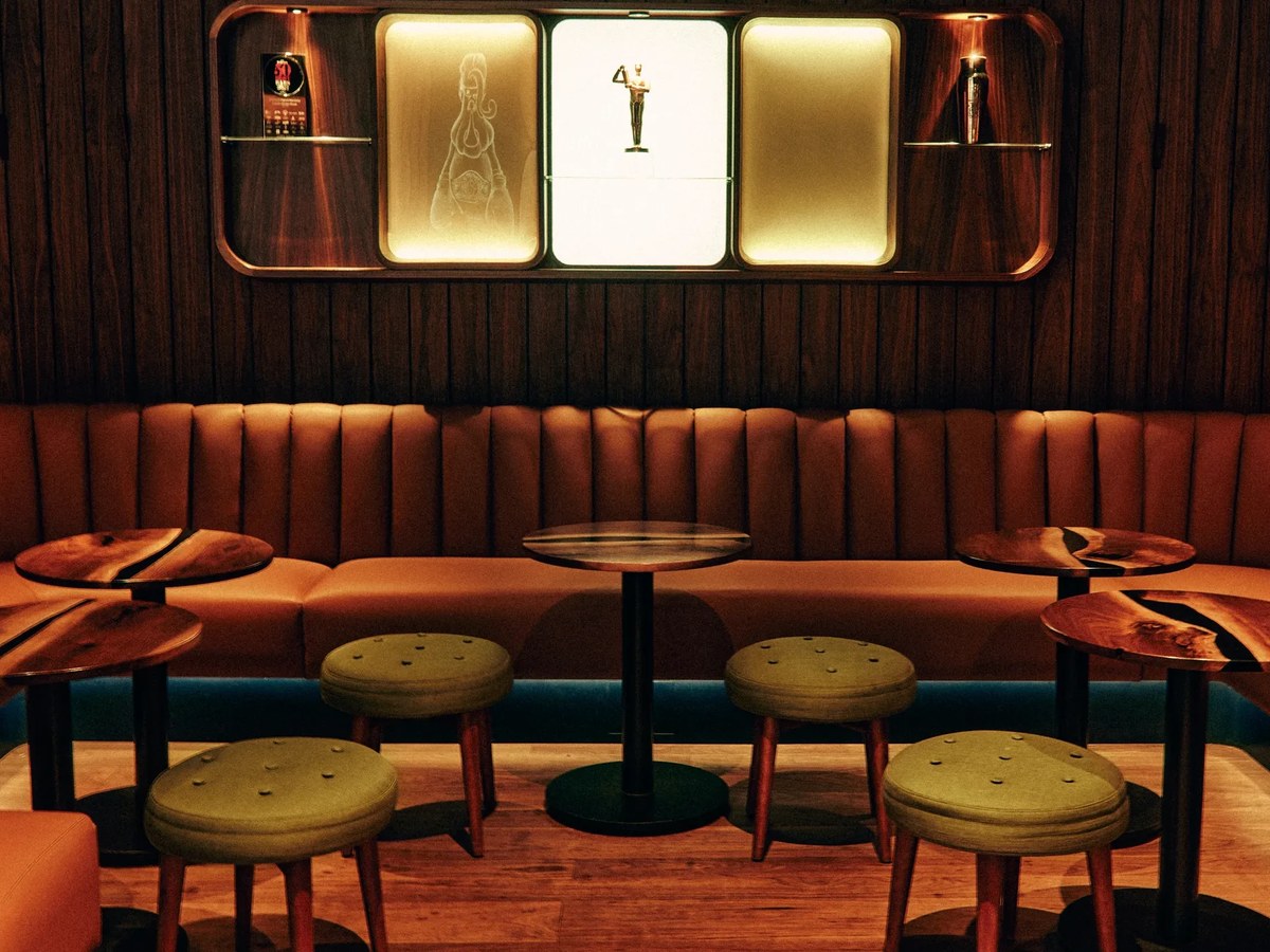 Double Chicken Please's interior, featuring an Art Deco-style wall fixture and burnt-orange banquette seating.