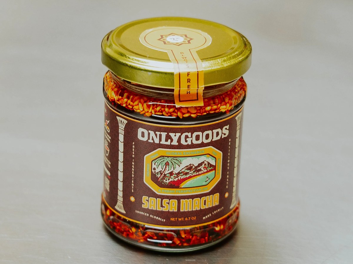A glass jar of Only Goods Salsa Macha (6.7 oz) with a gold lid, photographed on a neutral metal counter surface, the product name and brand are clear