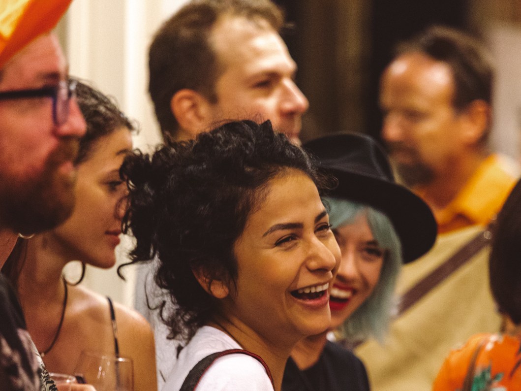 A crowd of festivalgoers laughing and holding drinks at what appears to be a Tales of the Cocktail event, confirmed by editorial alt-text 'Tales of th