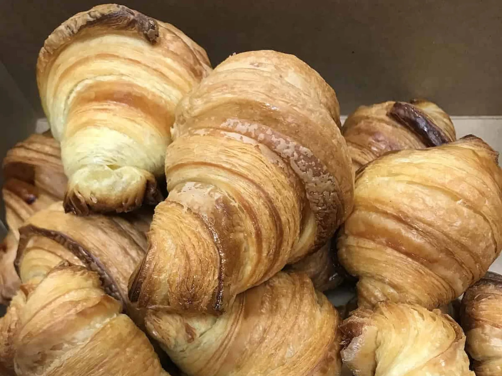 Croissants stacked in a box with golden-brown flaky layers.