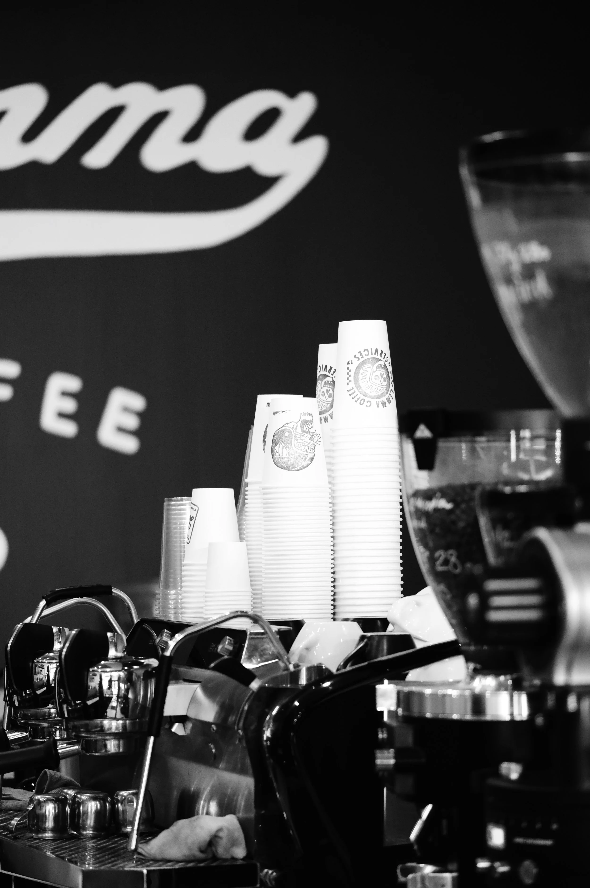Close-up of an espresso machine with group heads and portafilters in a coffee shop setting, published on Lemma Coffee Co's wholesale page under the 'S
