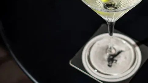 Limo Bar serves a classic martini in an elegant coupe glass, garnished with a single olive.