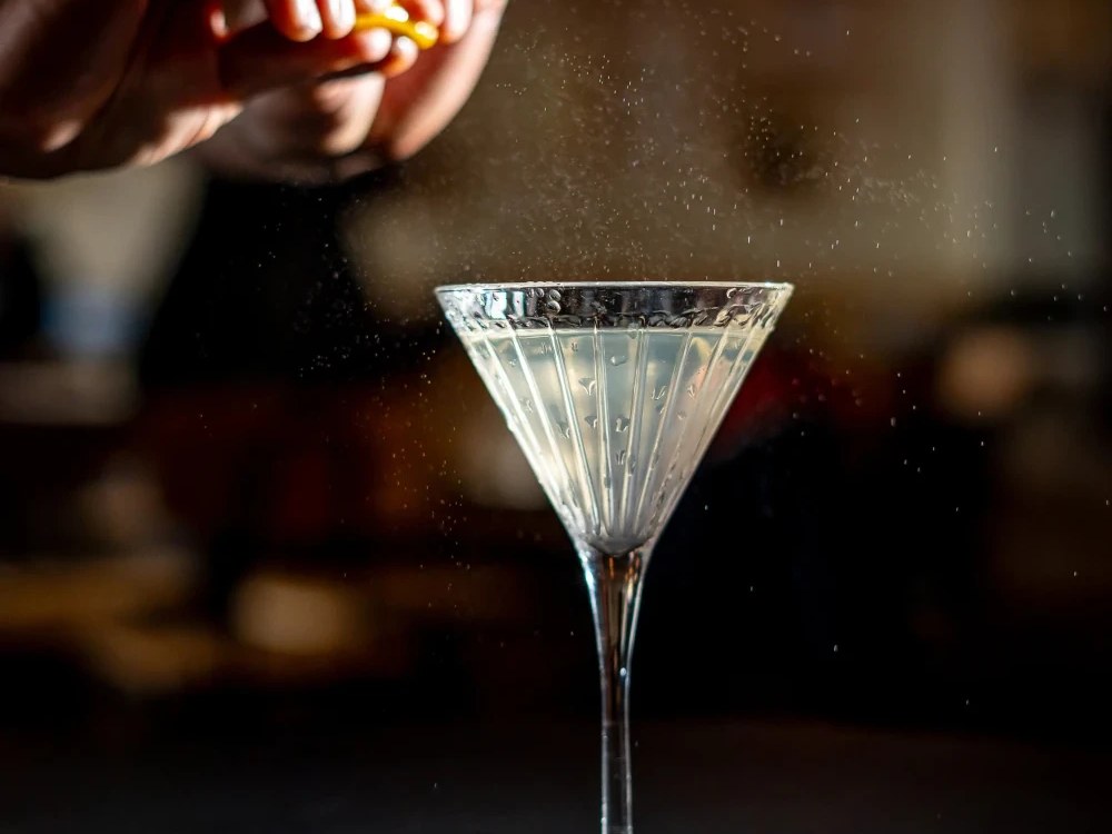 Limo Bar's Clean Dirty Martini, with a bartender squeezing citrus over the elegant glass.