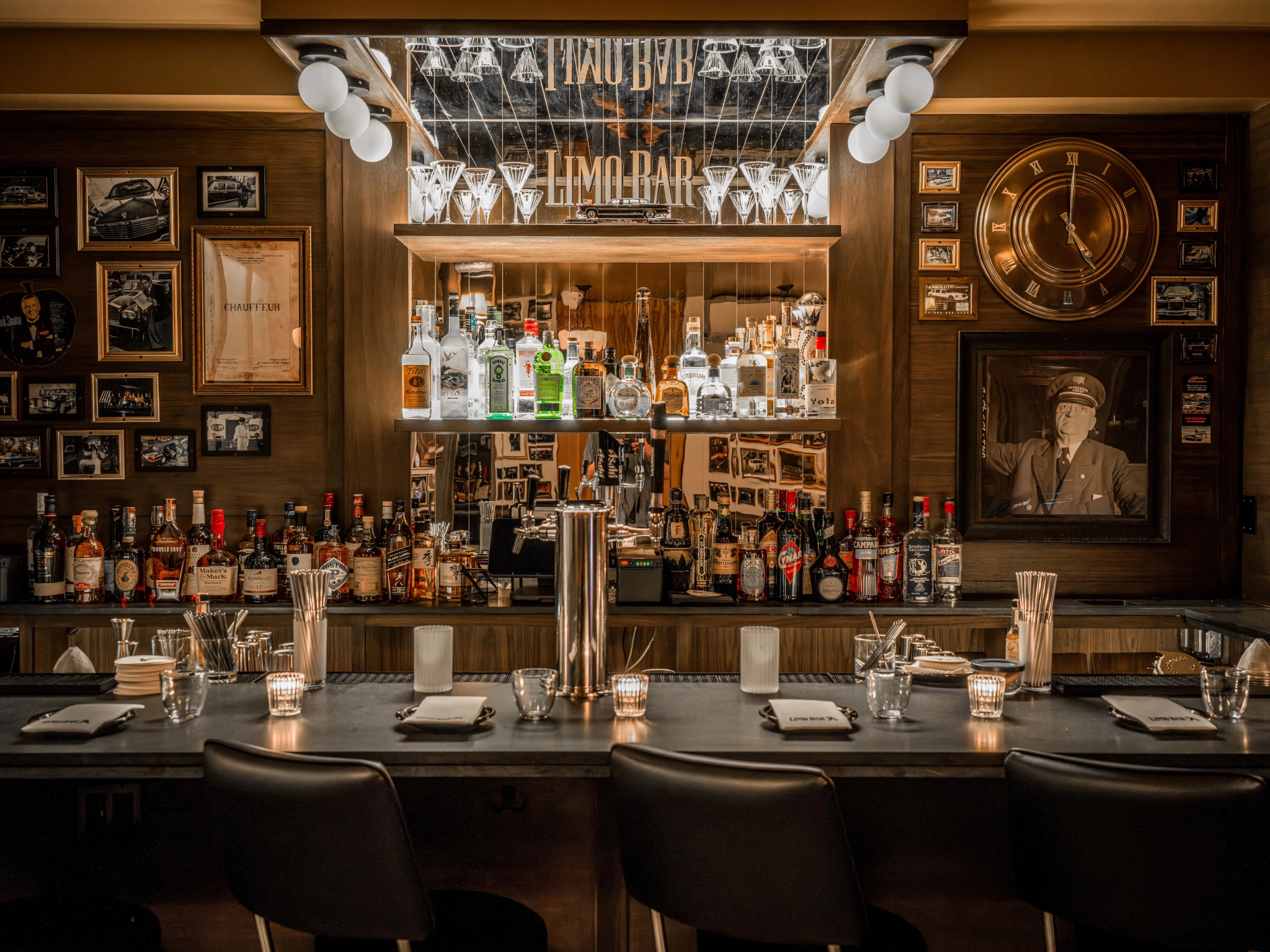 Limo Bar offers a polished interior with warm wood paneling, vintage photographs, and an extensive bottle display.