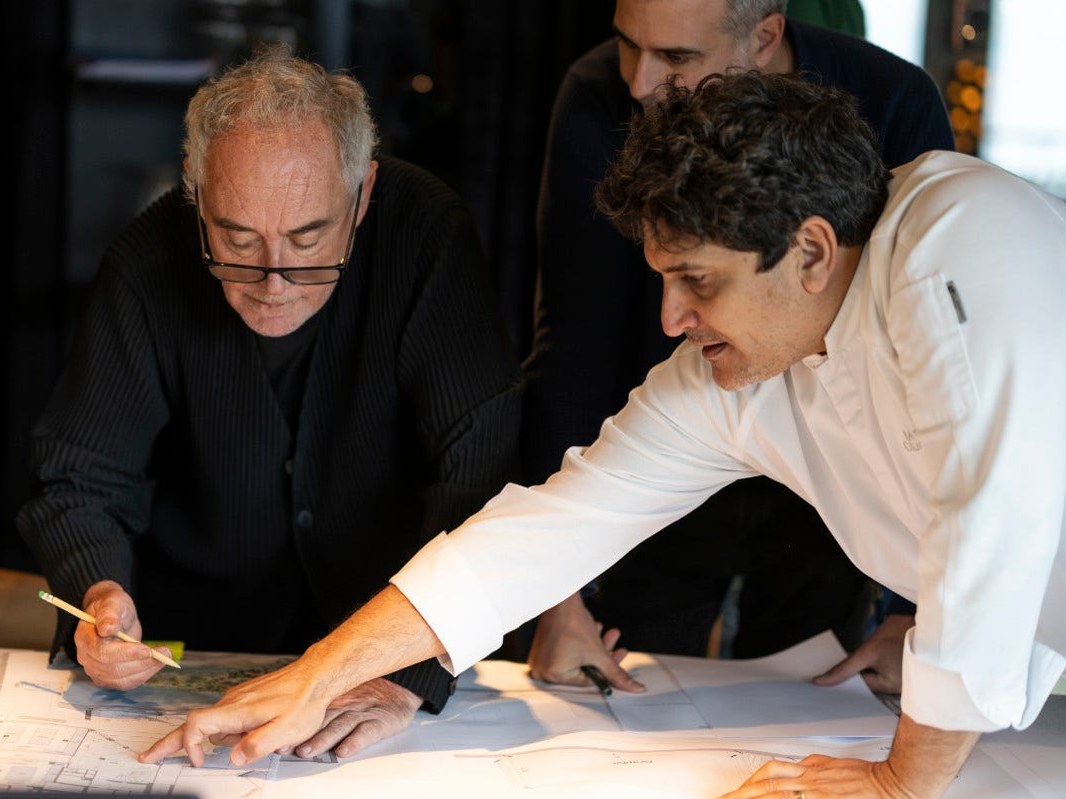 Three people examining architectural plans on a table.