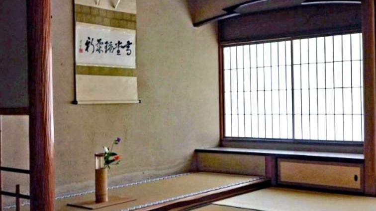 A licensed tea ceremony instructor's hands folding a white chakin cloth while wiping the rim of a ceramic chawan during formal temae preparation