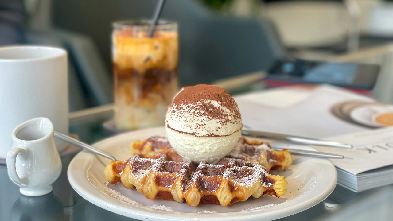 A Liège waffle dusted with powdered sugar topped with a spherical Korean mayak egg (half dusted with cocoa powder)
