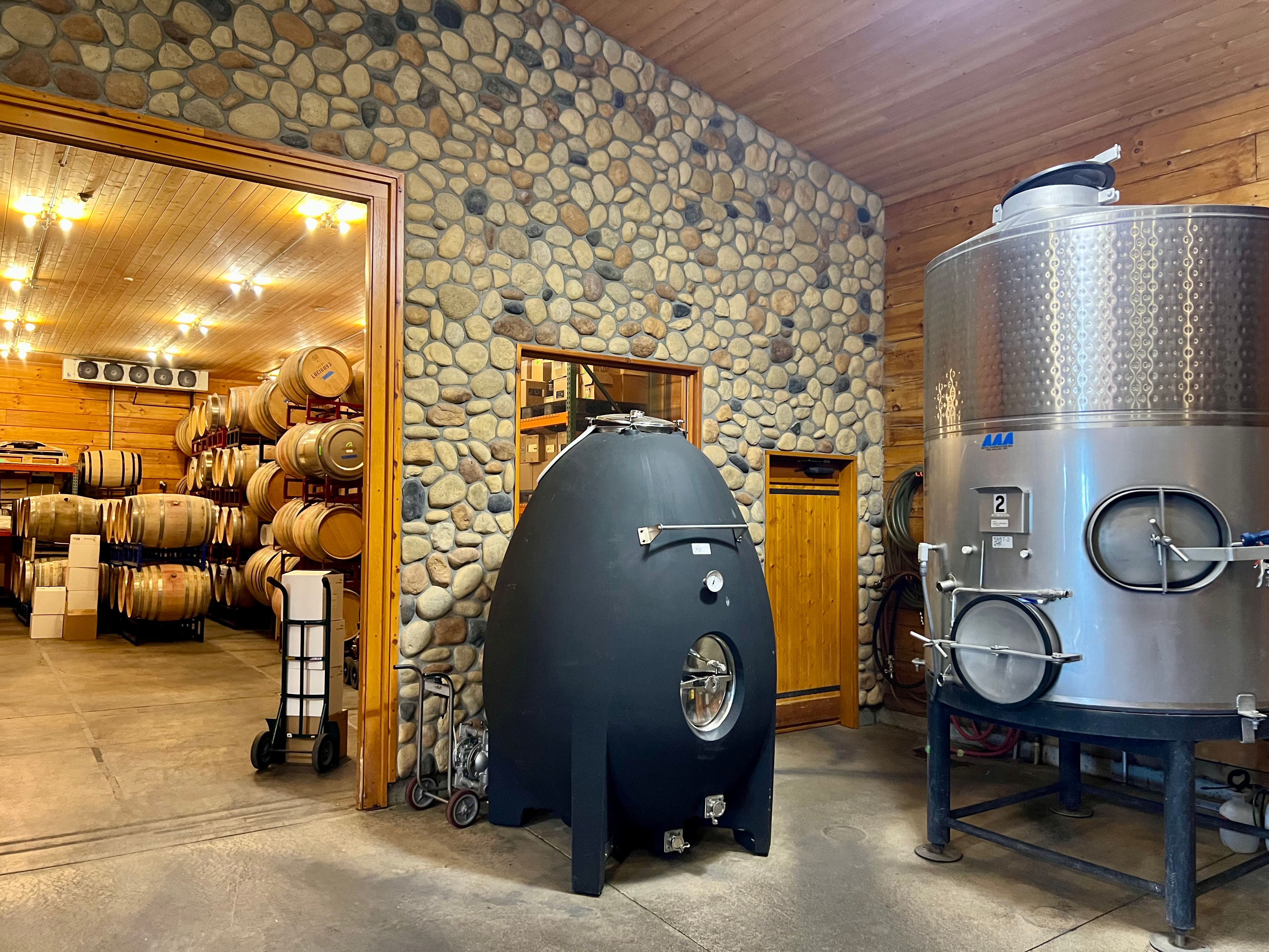 the inside of a winery with a concrete egg and wine barrels
