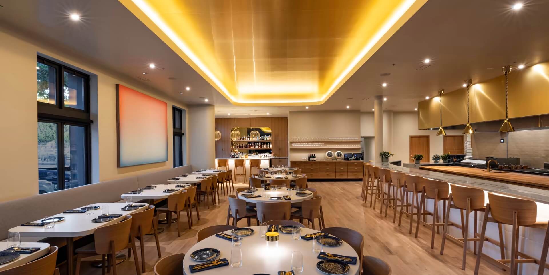 Modern upscale restaurant interior with ambient lighting, wooden furniture, and a well-stocked bar area