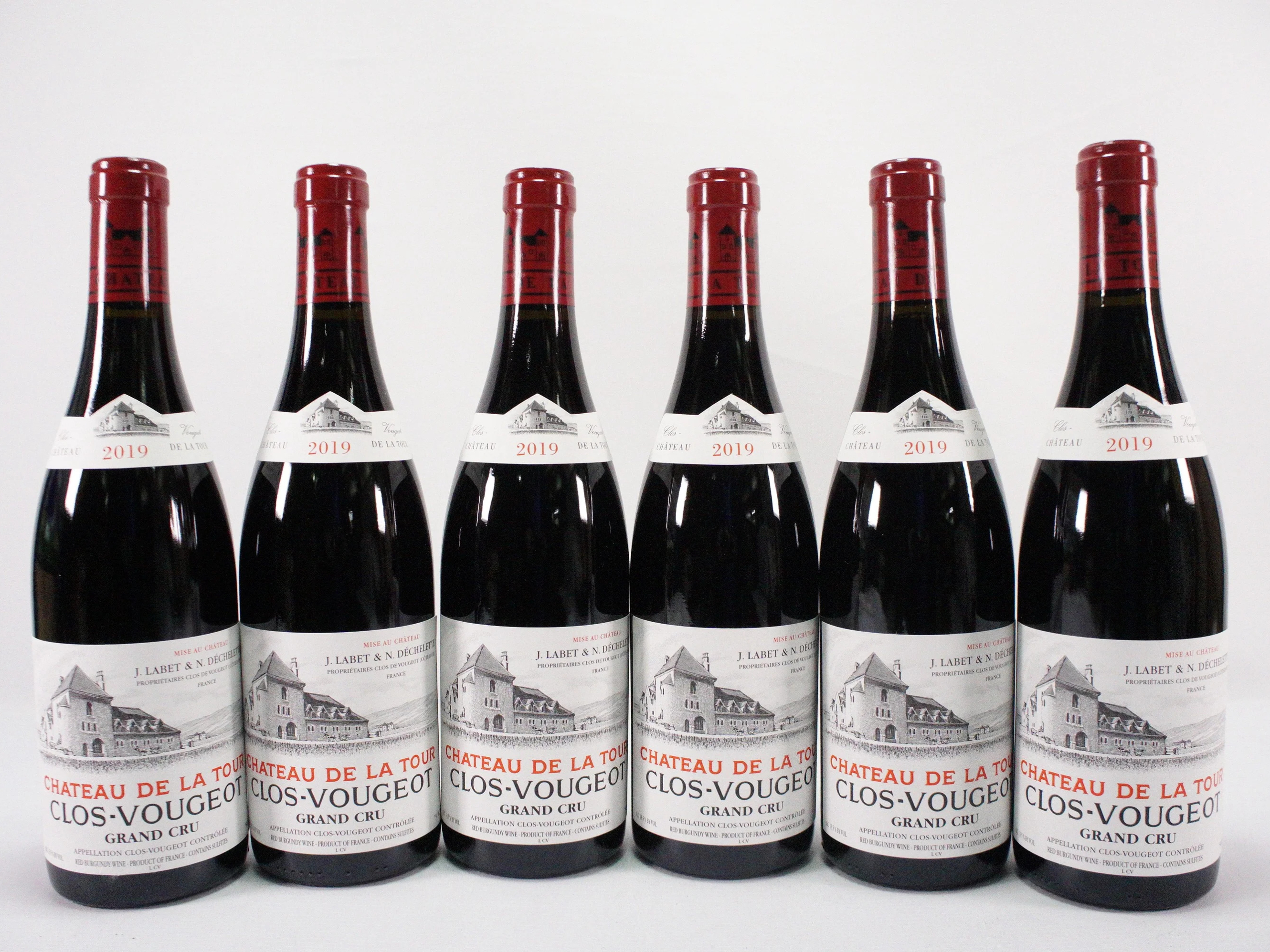 Six bottles of 2019 2018 Château de la Tour Clos-Vougeot Grand Cru, red labels, white and red text, arranged in a row against a white background.