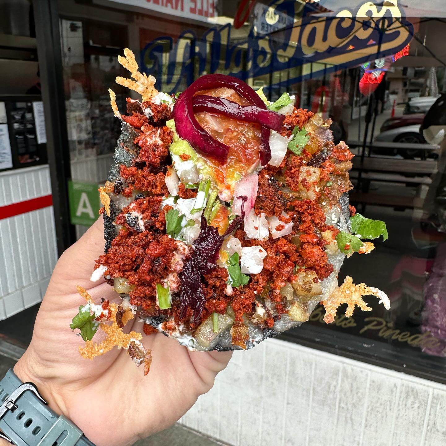 A behemoth of a taco from Villa's Tacos - a blue corn tortilla topped with chorizo, diced onions, cilantro, crema, cotija, and guacamole