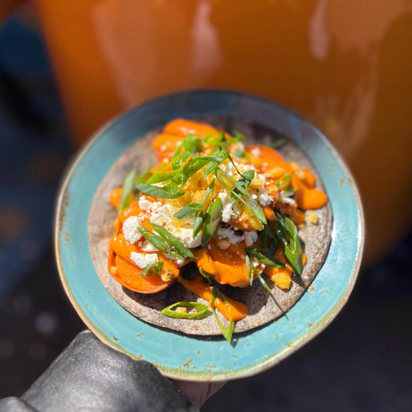 Guerrilla Tacos' sweet potato tacos on a blue corn tortilla with almond & Cashew Chile, Feta Cheese, Fried Corn and Onion