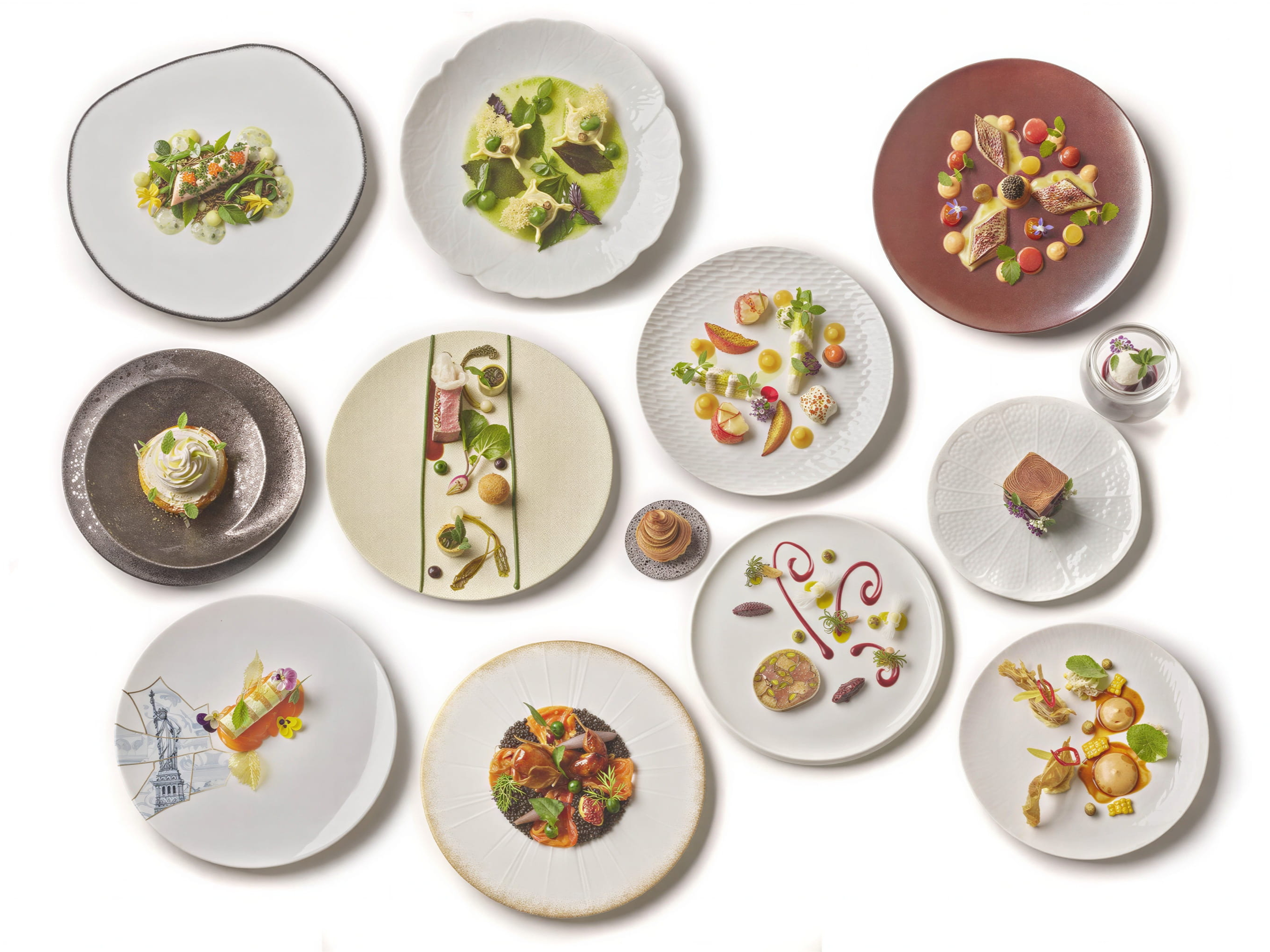 Aerial view of a selection of dishes from the summer 2025 menu at Daniel NYC, featuring vibrant colors and intricate presentations, set against a white background.