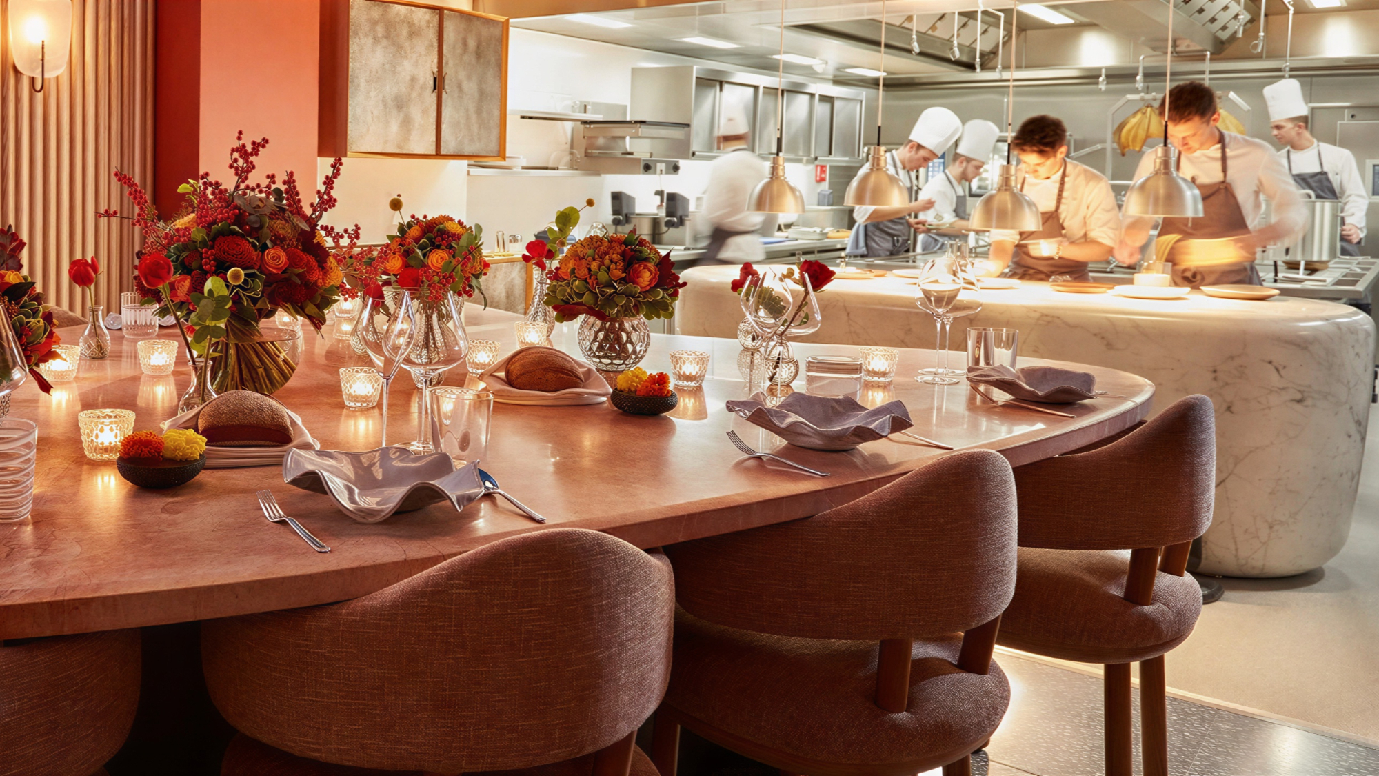 Elegant restaurant setting with flower arrangements on tables, dim lighting, and chefs working in an open kitchen, exuding a cozy ambiance.