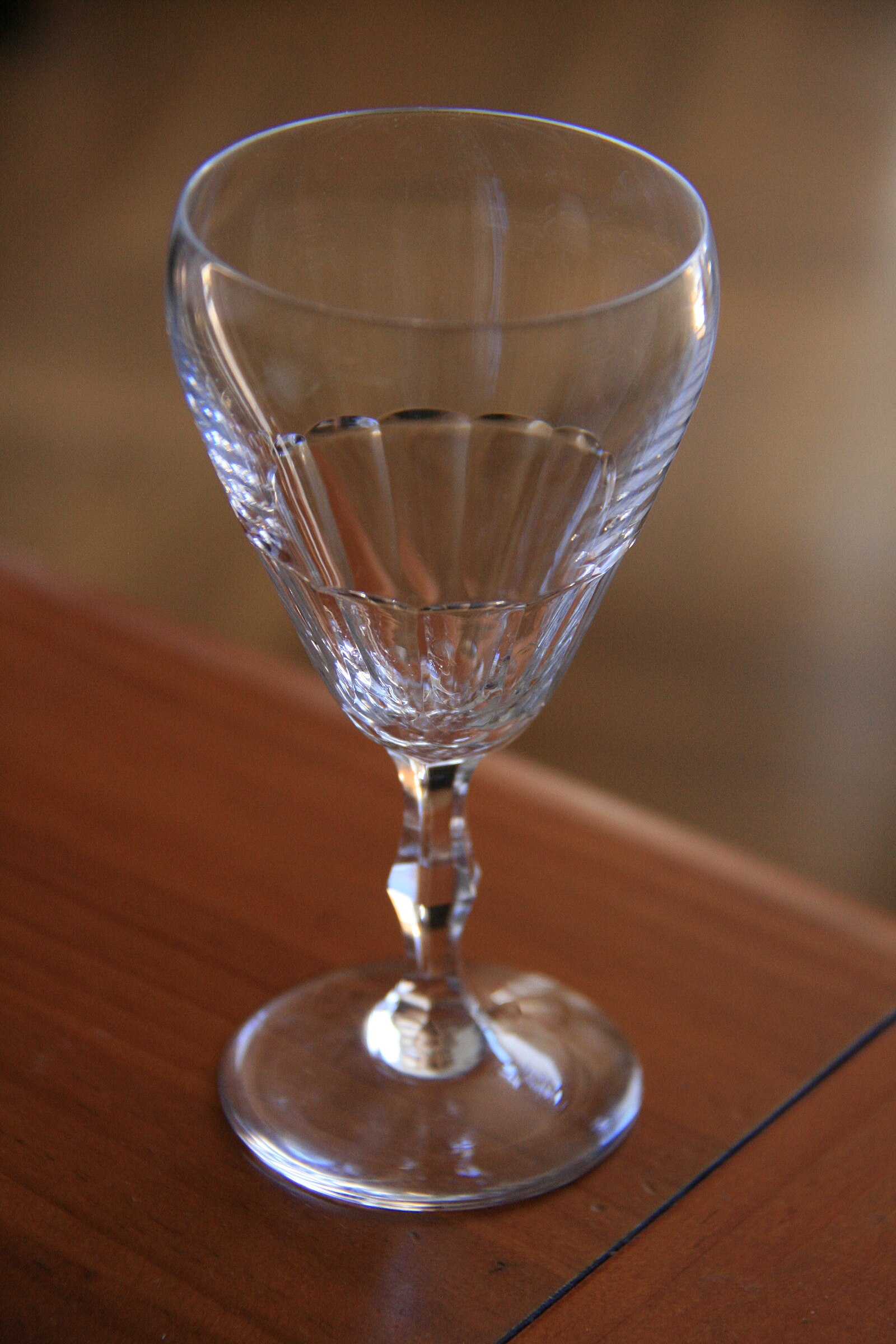 A clear cut-glass goblet made by Josephinenhütte on a wooden surface