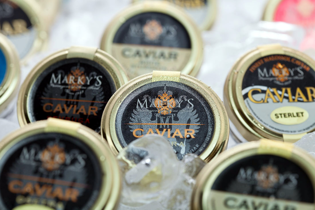 An open Marky's Caviar tin with a mother-of-pearl spoon